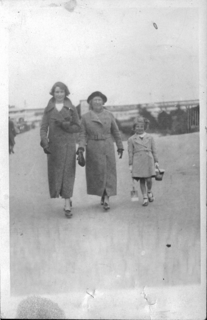 'Three female generations' - the bucket & spade give us a clue this was near a beach but the picture is so poor no idea where.  The lady ion tghe left could well be Alice which might well mean the child is my mum (Irene) but who is the older lady, I'm guessing (?) mum's nan, but which one?